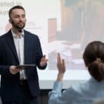 a man in a suit giving a presentation to a woman